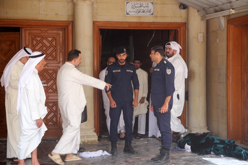 Kuwaiti security forces stand next to a body wrapped in shrouds as they inspect the site of a suicide bombing that targeted the Shiite Al-Imam al-Sadeq mosque during Friday prayers on June 26, 2015, in Kuwait City. The Islamic State group-affiliated group in Saudi Arabia, calling itself Najd Province, said militant Abu Suleiman al-Muwahhid carried out the attack, which it claimed was spreading Shiite teachings among Sunni Muslims. AFP PHOTO / YASSER AL-ZAYYAT