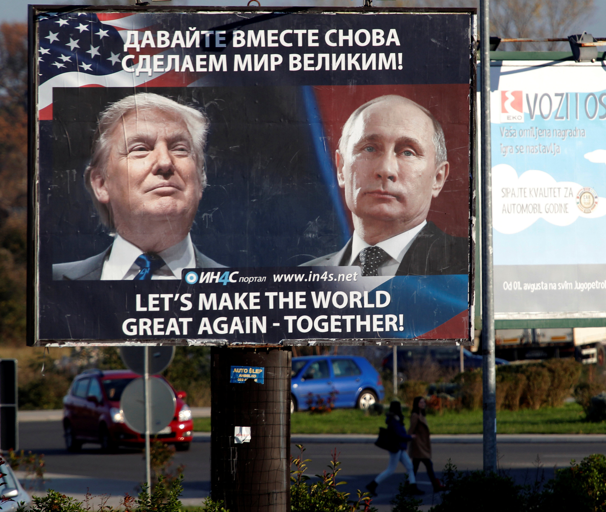 Pedestrians cross the street behind a billboard showing a pictures of US president-elect Donald Trump and Russian President Vladimir Putin in Danilovgrad, Montenegro, November 16. 2016. REUTERS/Stevo Vasiljevic